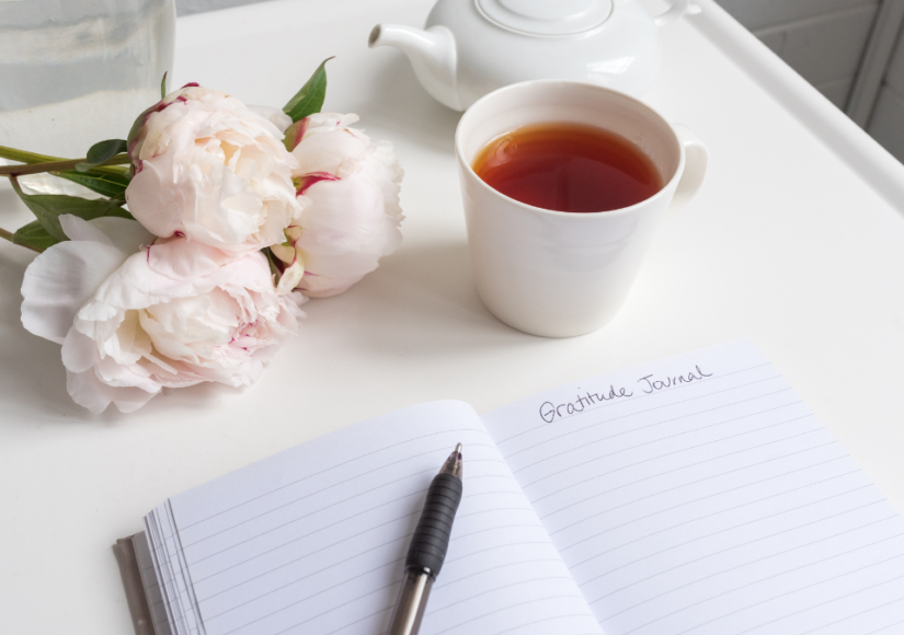 Image of a desk with notepad and pen and tea